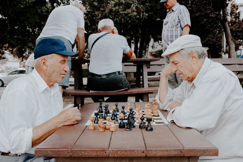 Two older men sitting at a table with a chessboard